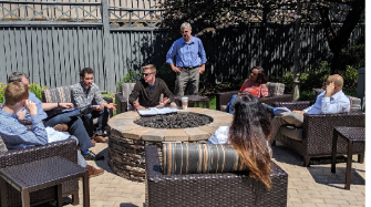 A professor oversees a group discussion outside