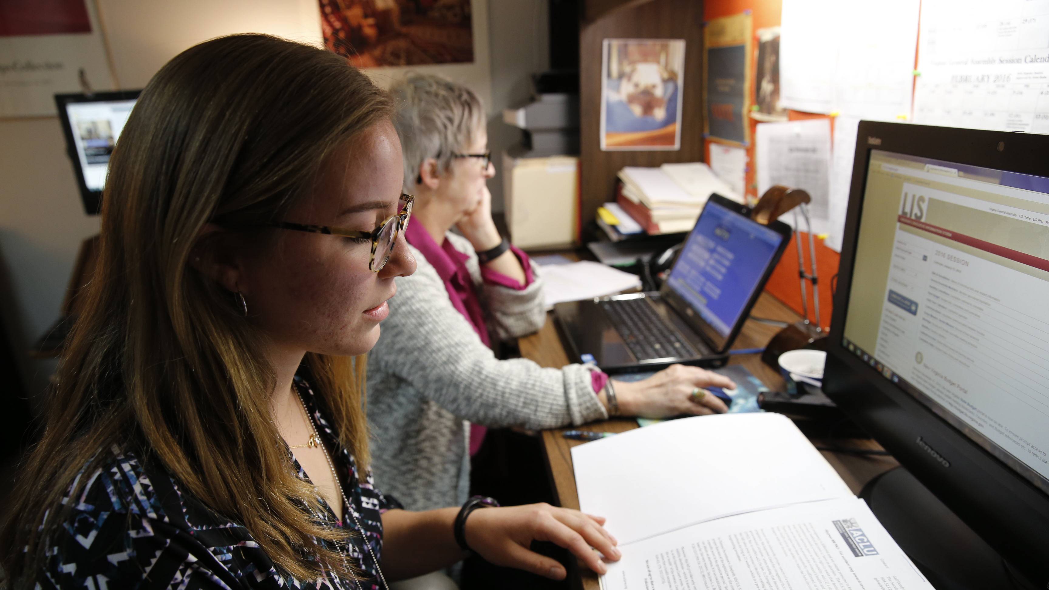 Virginia Capitol Semester Alumna Julia Carney looks over legislative email between meetings. Next to her is Deborah L. Sherman, legislative aide to Del. Vivian E. Watts. 