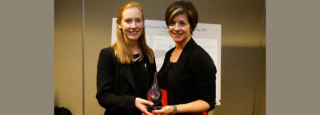 Laura Howell accepts congratulations from Meghan Gough, Ph.D., chair of the Urban and Regional Studies/Planning program, in front of her project poster.